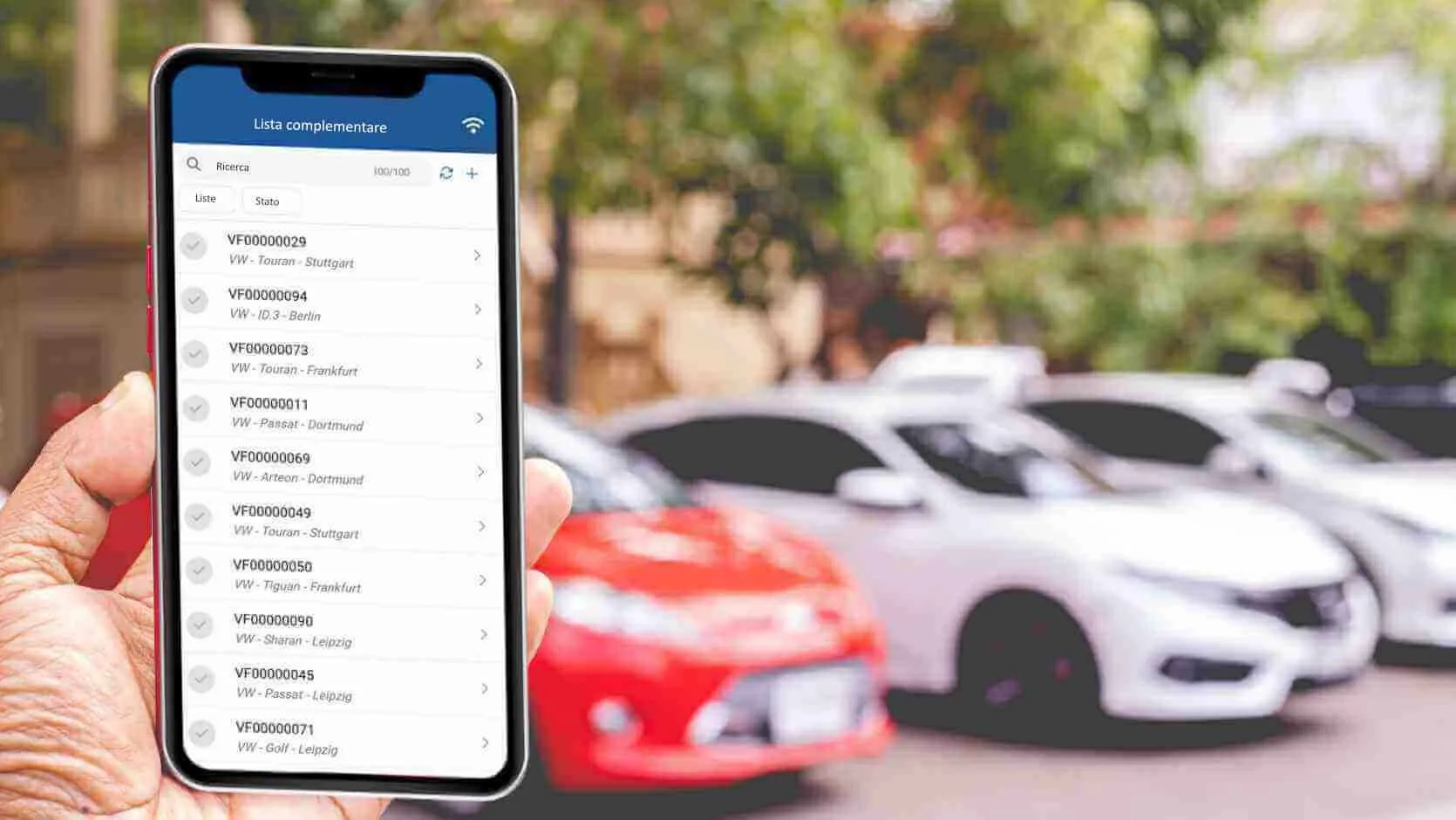 Caratteristiche dell'Lista complementare nell'App Inventario ex:stock Smartphone con elenco dell'inventario e veicoli sullo sfondo